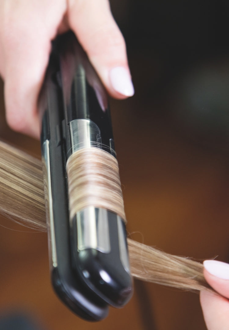 La piastra liscia una ciocca di capelli biondi