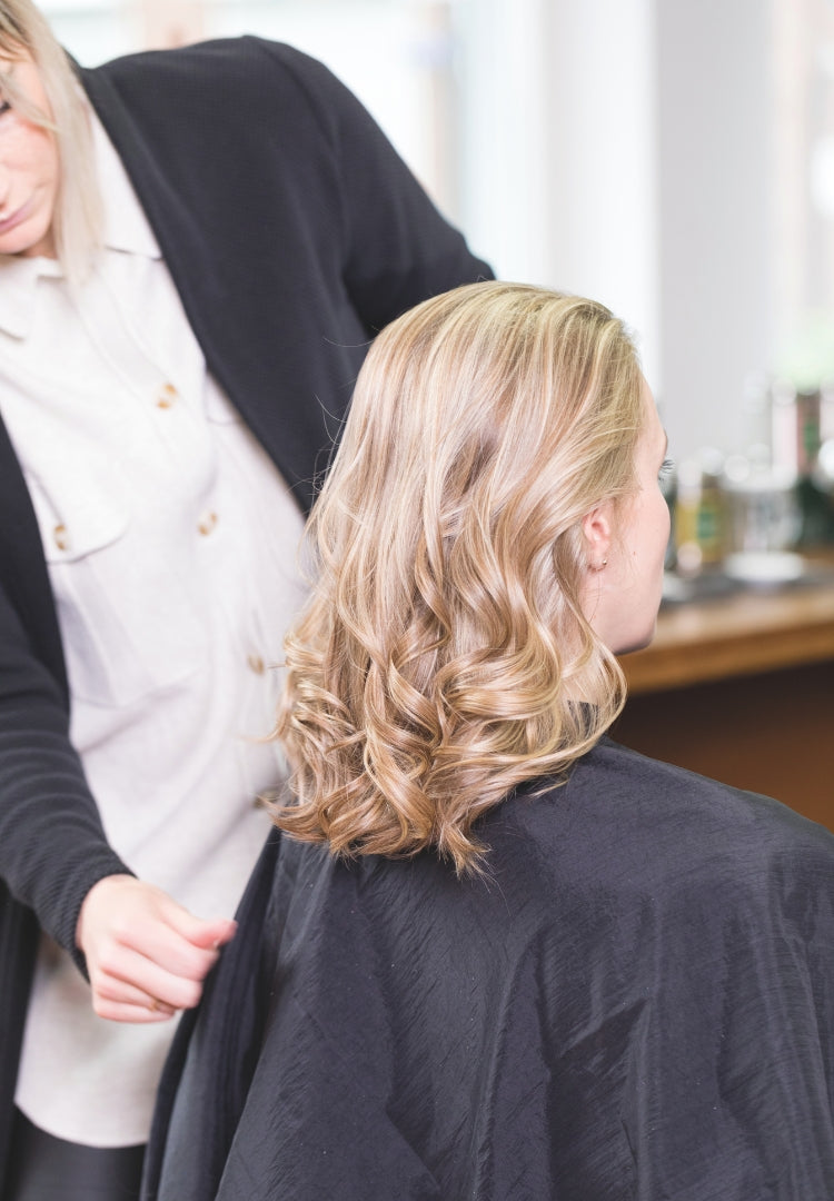 Parrucchiera acconcia capelli biondi e mossi