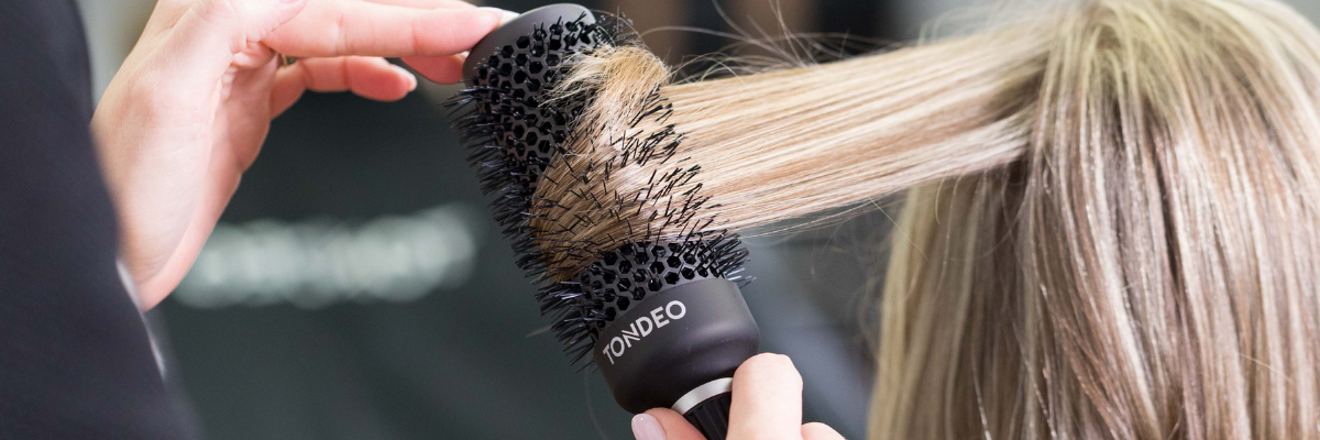 Friseur bürstet blonde Haare professionell