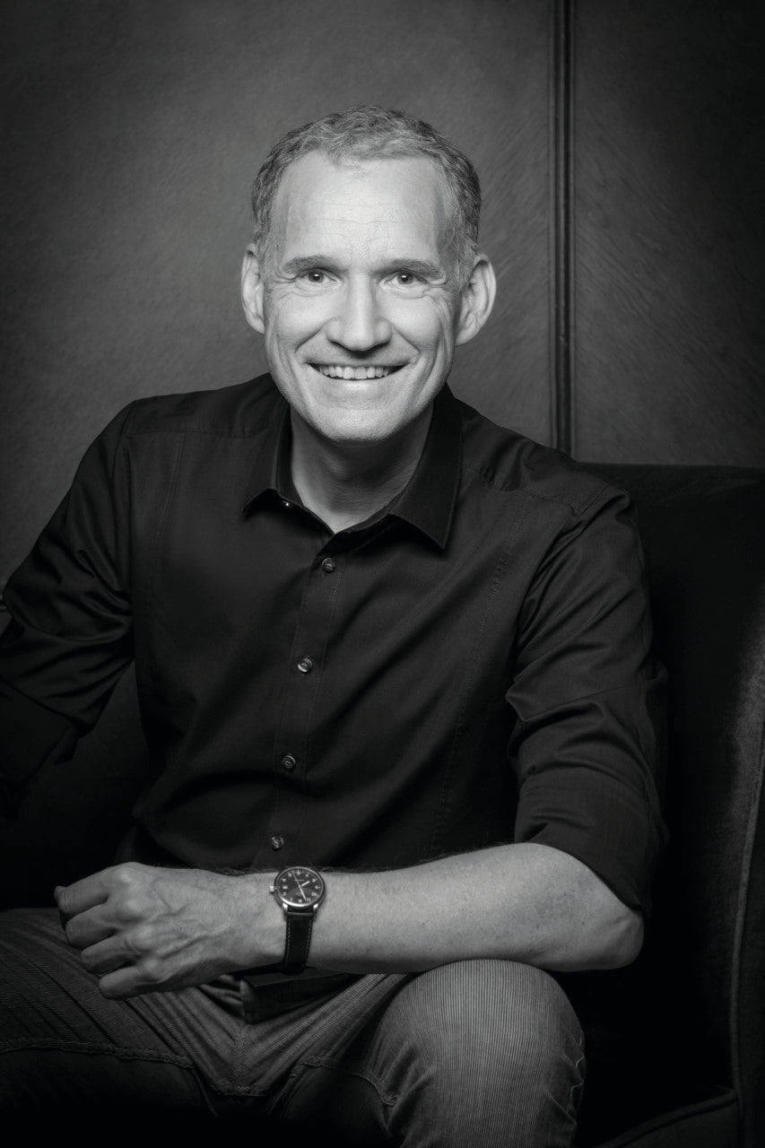 Mann lächelt, sitzt auf Stuhl