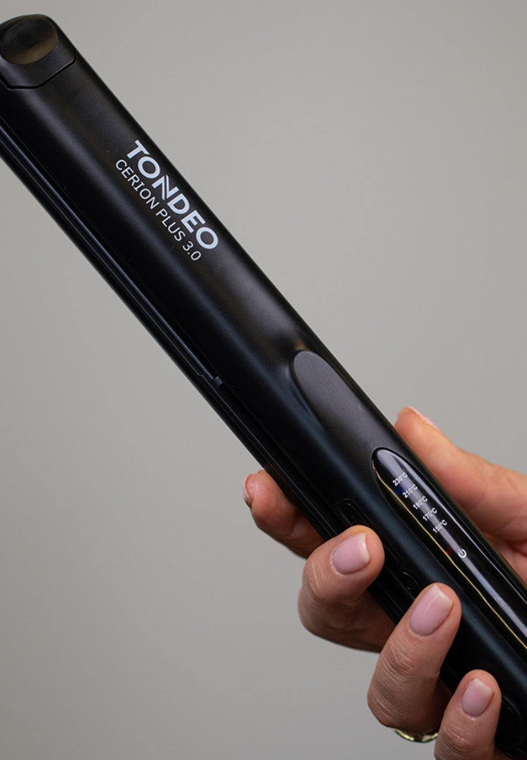 Mano sosteniendo una plancha de pelo negra Tondeo