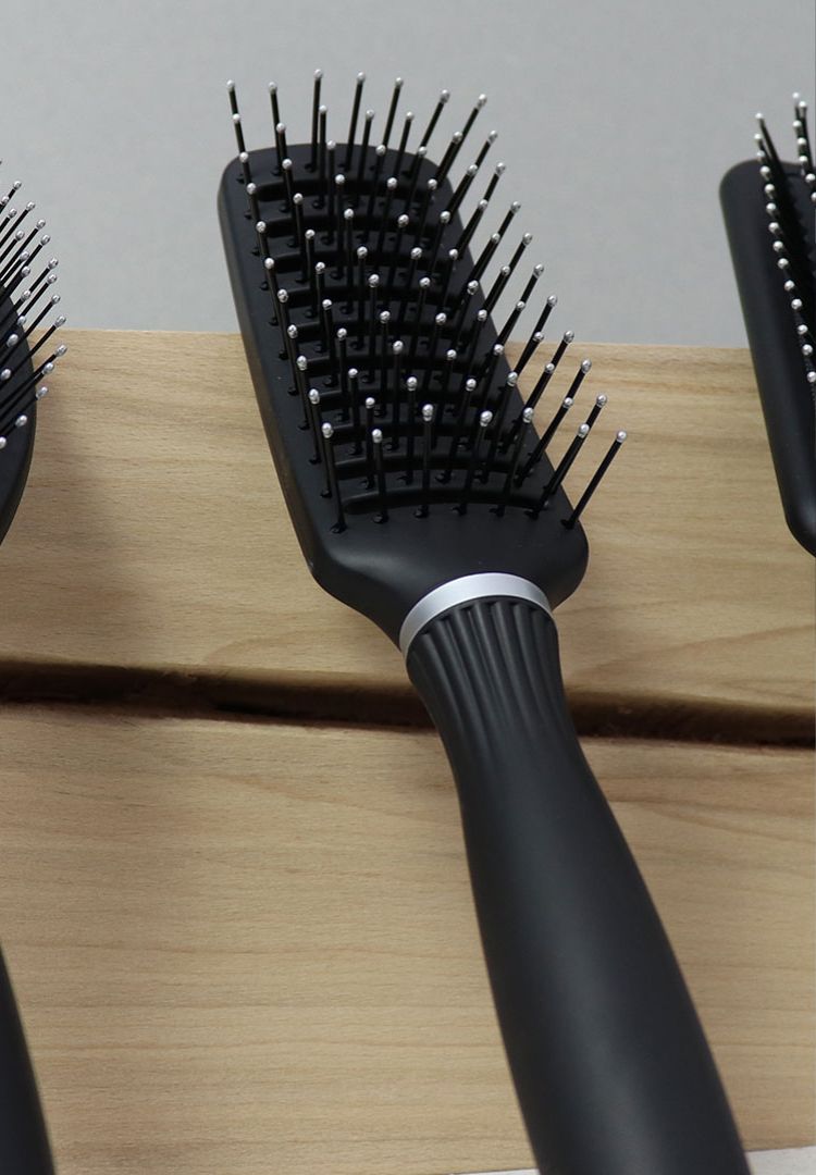 Schwarze Haarbürste auf Holzoberfläche