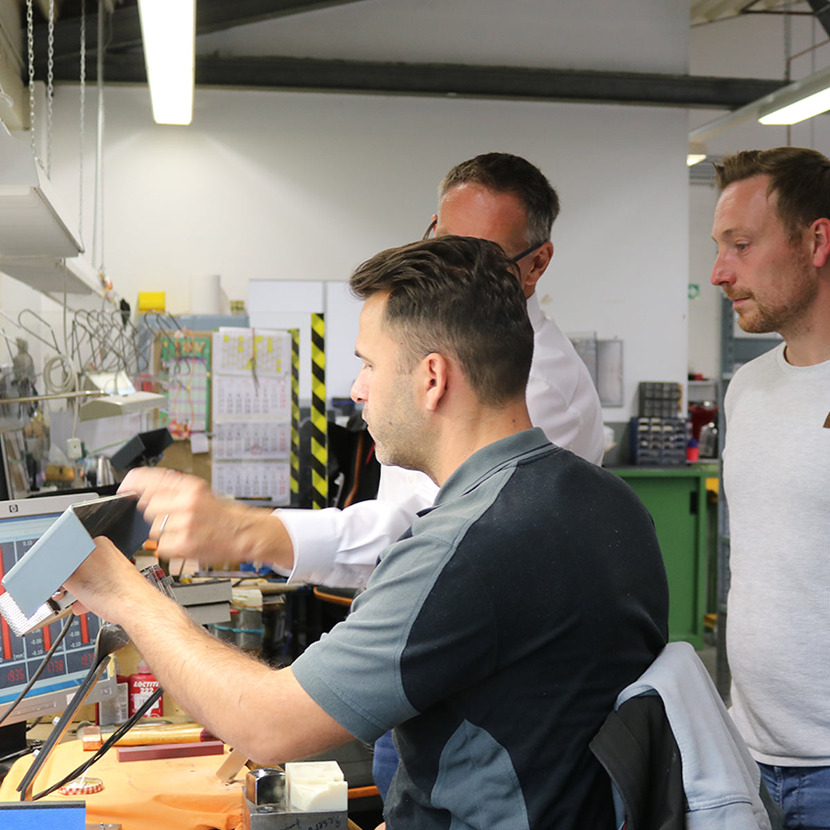 Drei Männer begutachten Friseurscheren.