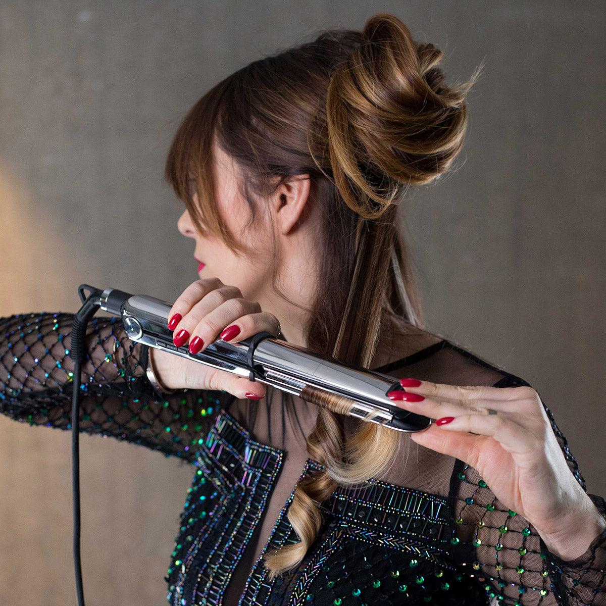 Mujer peina el cabello con una plancha alisadora.