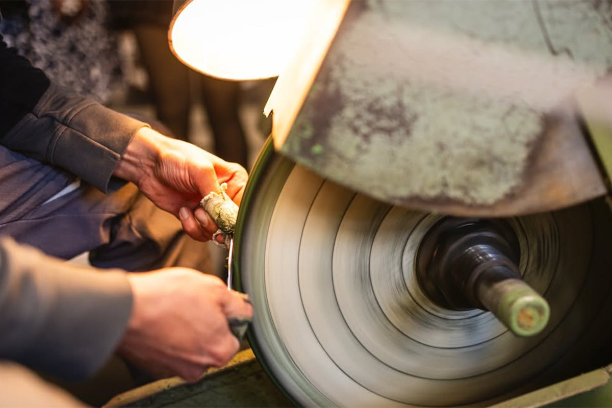 Hand schleift Friseurschere an Schleifmaschine